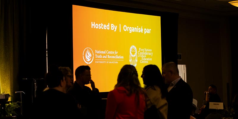 Silhouette of guests against bright screen showing NCTR logo